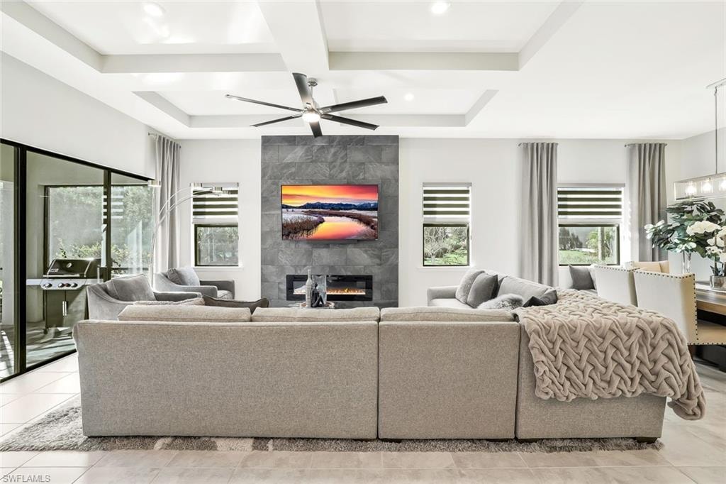 Great room featuring a tray ceiling, contemporary ceiling fan, and a stone-clad accent wall with an electric fireplace