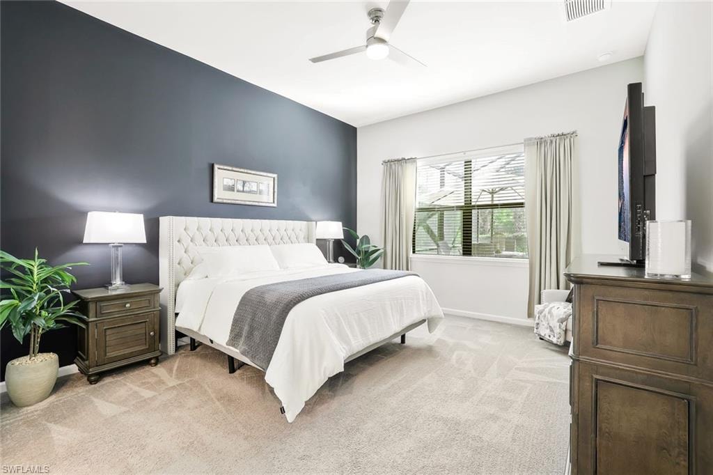 Bedroom featuring a tufted upholstered headboard, a dark accent wall, and light-toned carpeting