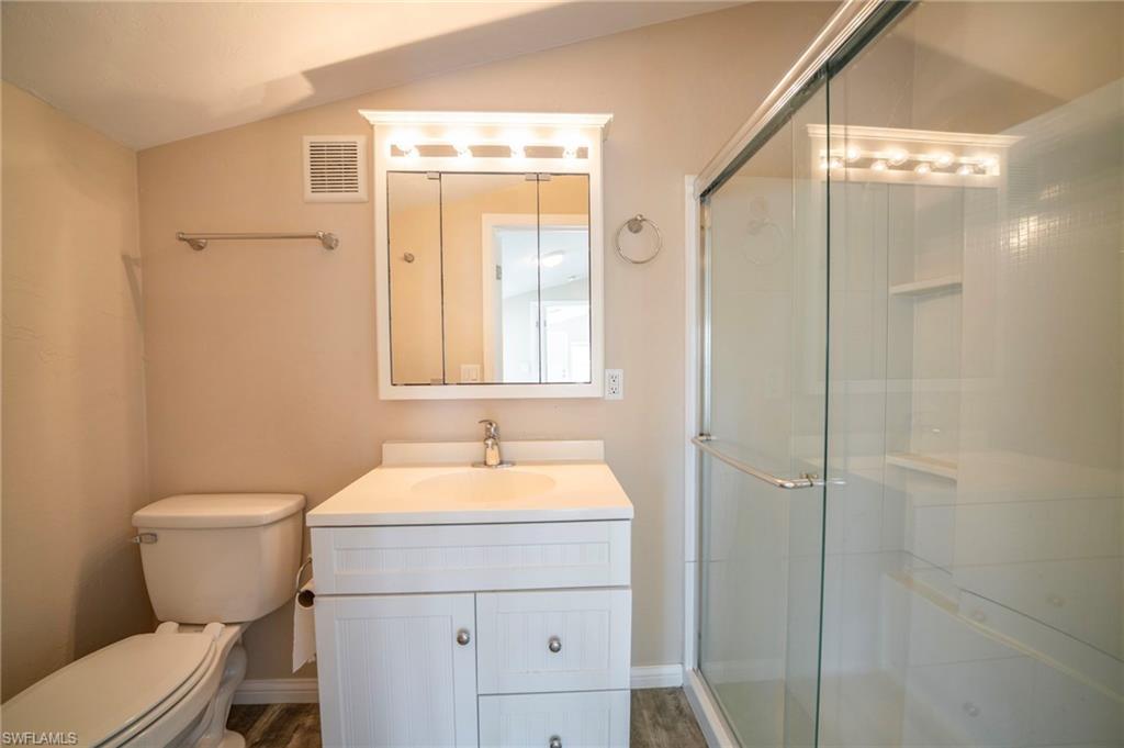 Bathroom featuring vanity, an enclosed shower, and toilet