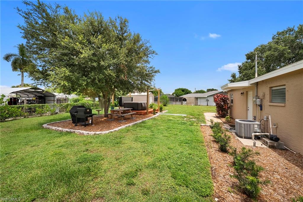 Expansive rear yard featuring a large mature tree, a defined mulched area, and a wood patio deck
