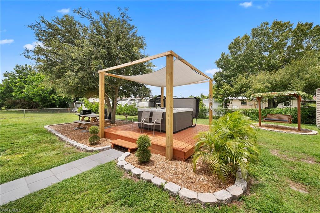 Expansive backyard featuring a wood deck with hot tub and pergola, a separate garden swing, and a picnic table