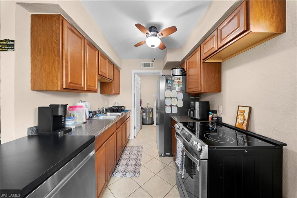 Galley kitchen featuring wood cabinetry, granite-style countertops, and a full suite of stainless steel appliances