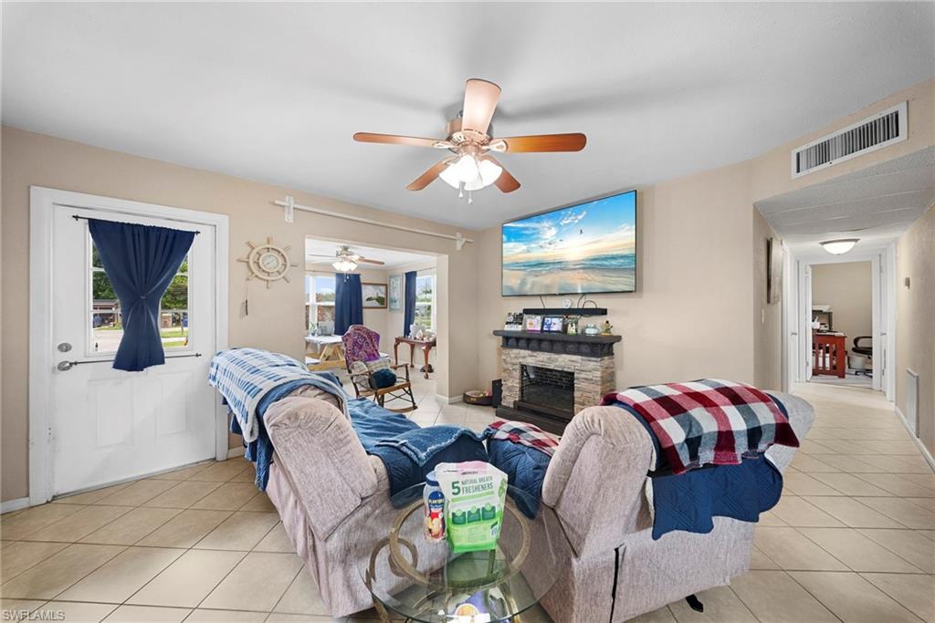 Living area featuring tile flooring, a stone-front fireplace, recessed lighting, and a ceiling fan