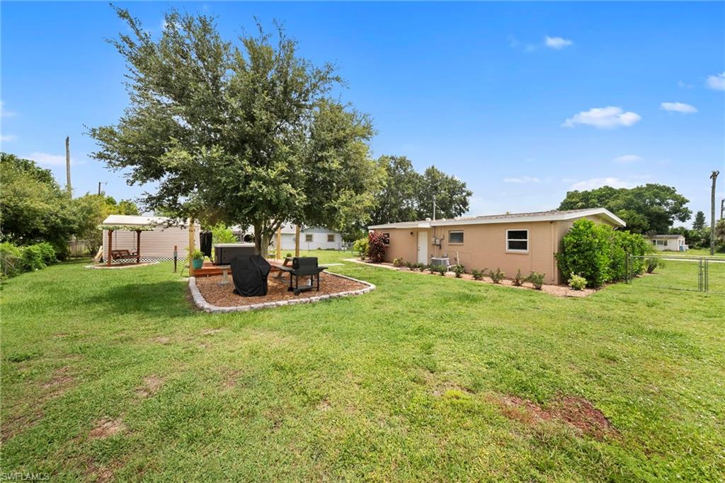 Spacious backyard featuring a substantial tree and a separate patio area with a pergola