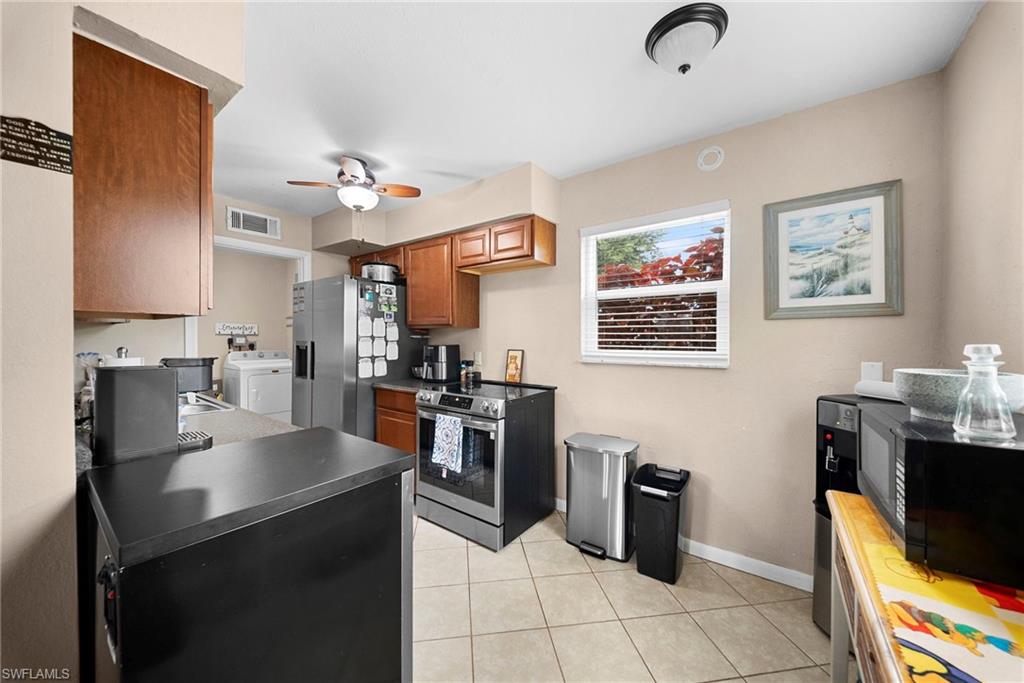 Kitchen featuring tile flooring, wood cabinetry, stainless steel appliances, and a ceiling fan