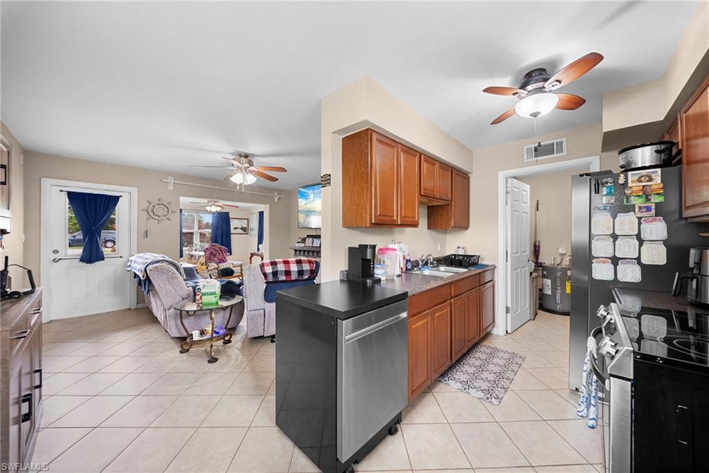 Kitchen featuring wood-finish cabinetry, stainless steel appliances, and a tile floor