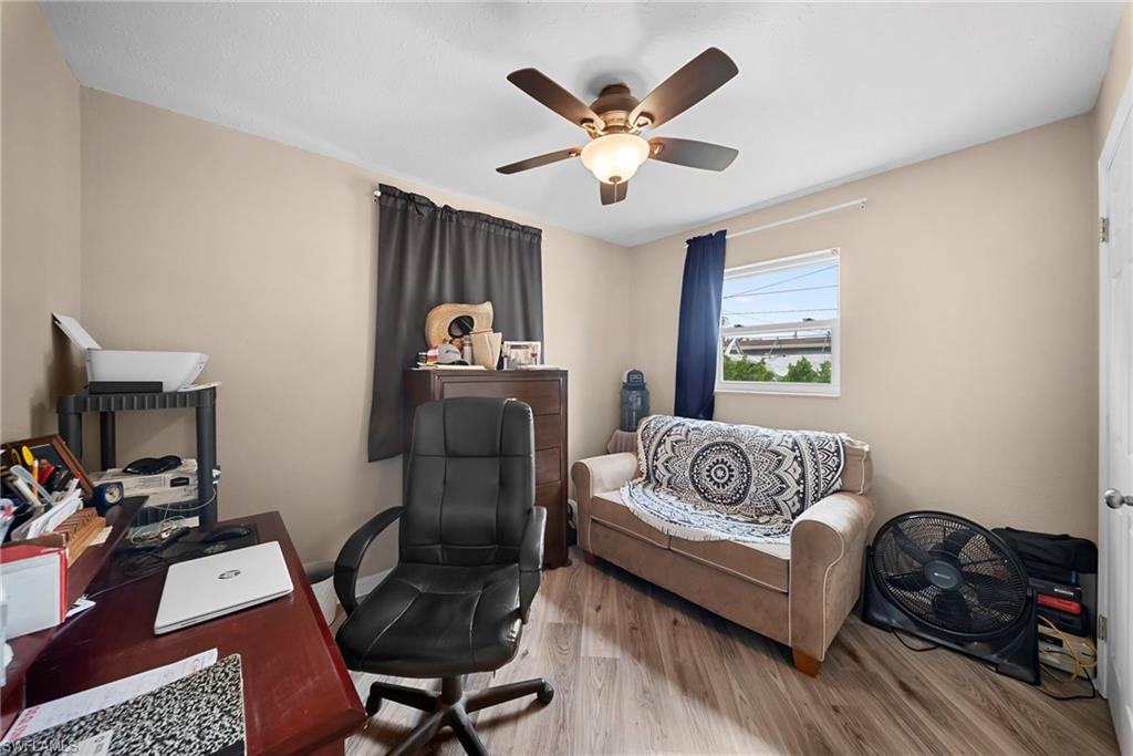 Bedroom featuring neutral wall tones, wood-finish flooring, a ceiling fan with integrated lighting, and a single window with vertical blinds