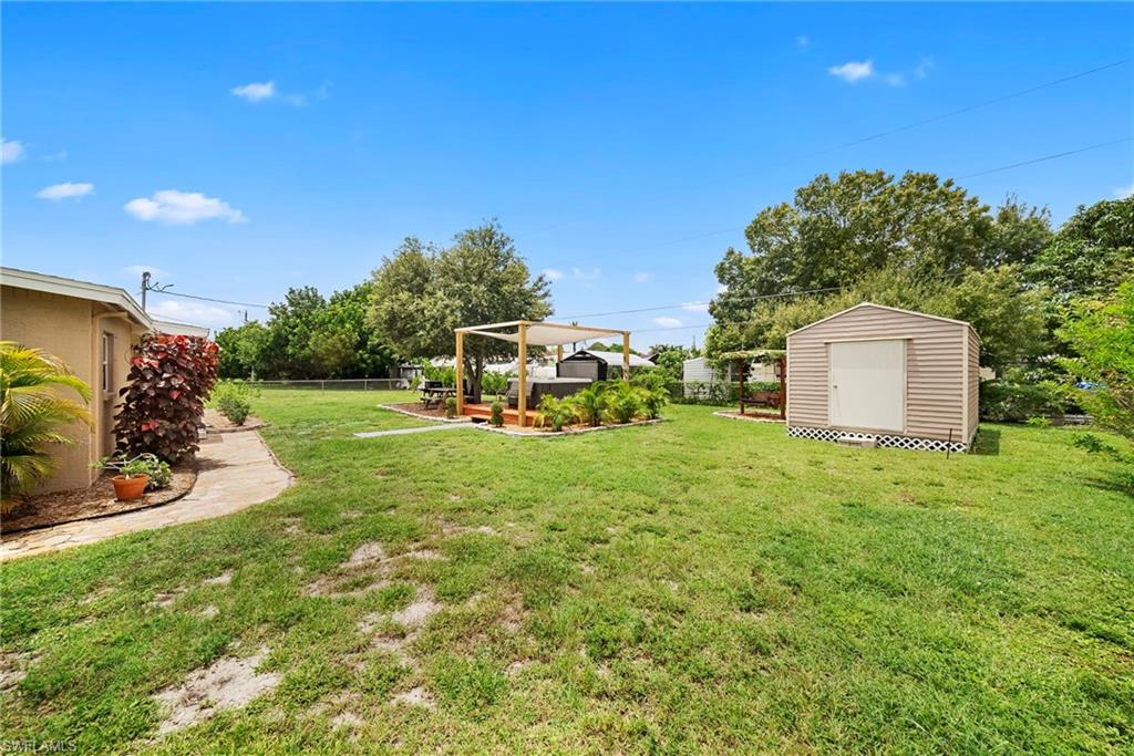 Expansive backyard featuring a lush lawn, a detached storage shed, a wooden deck with a pergola, and mature landscaping