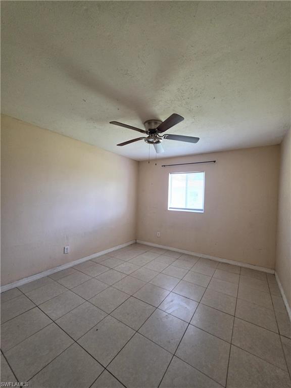 Spacious room featuring tile flooring, a window providing natural light, and a ceiling fan with integrated lighting