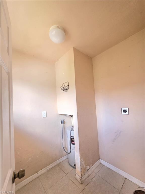 Utility room featuring a water heater, tiled flooring, and a ceiling-mounted light fixture
