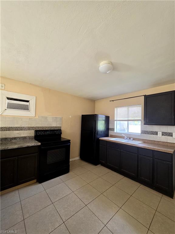 Kitchen featuring tile flooring, dark cabinetry, and black appliances