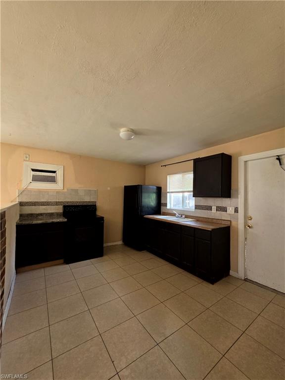 Kitchen featuring tile flooring, dark cabinetry, and light-toned countertops