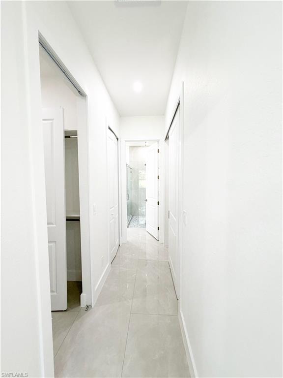Bright hallway featuring recessed lighting and light-toned tile flooring