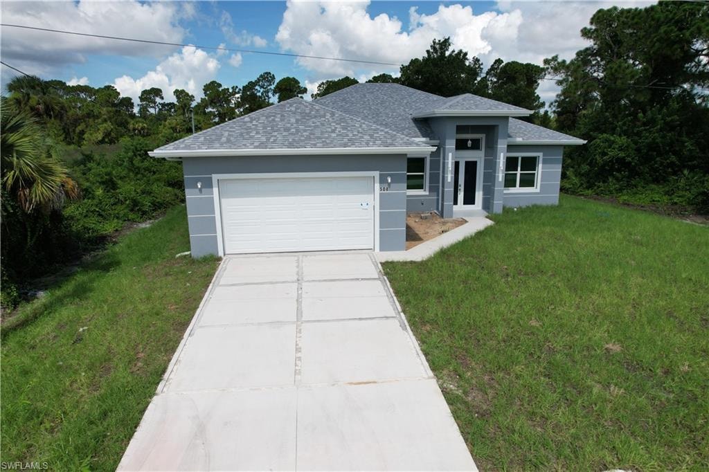 Contemporary residence featuring a light gray exterior, an attached garage, a paved driveway, and a covered entry