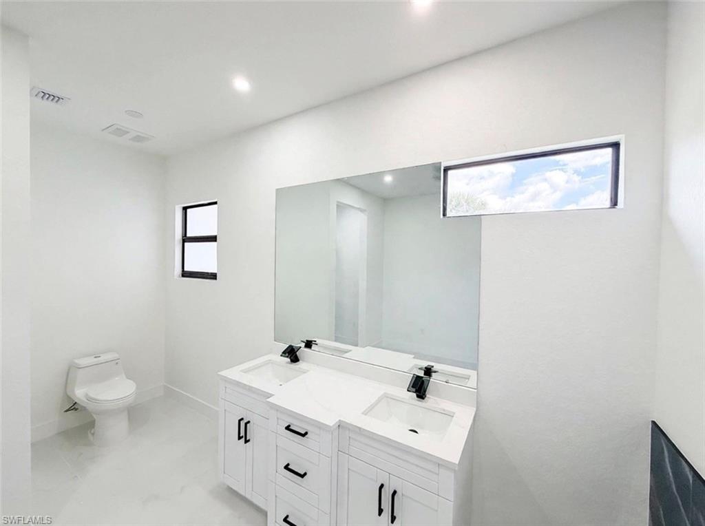 Double vanity with white cabinetry, quartz-style countertop, and matte black fixtures