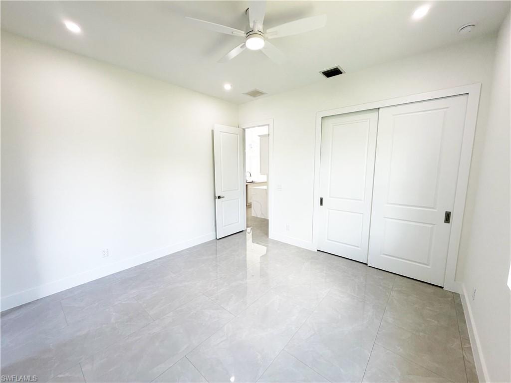 Spacious interior room featuring white walls, gray large-format tile flooring, and a modern ceiling fan