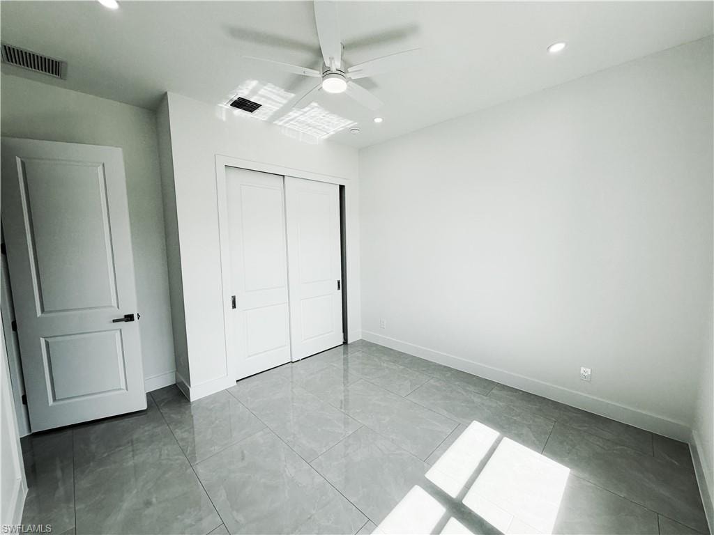 Room featuring large format grey tile flooring, white walls, and a contemporary ceiling fan with integrated lighting