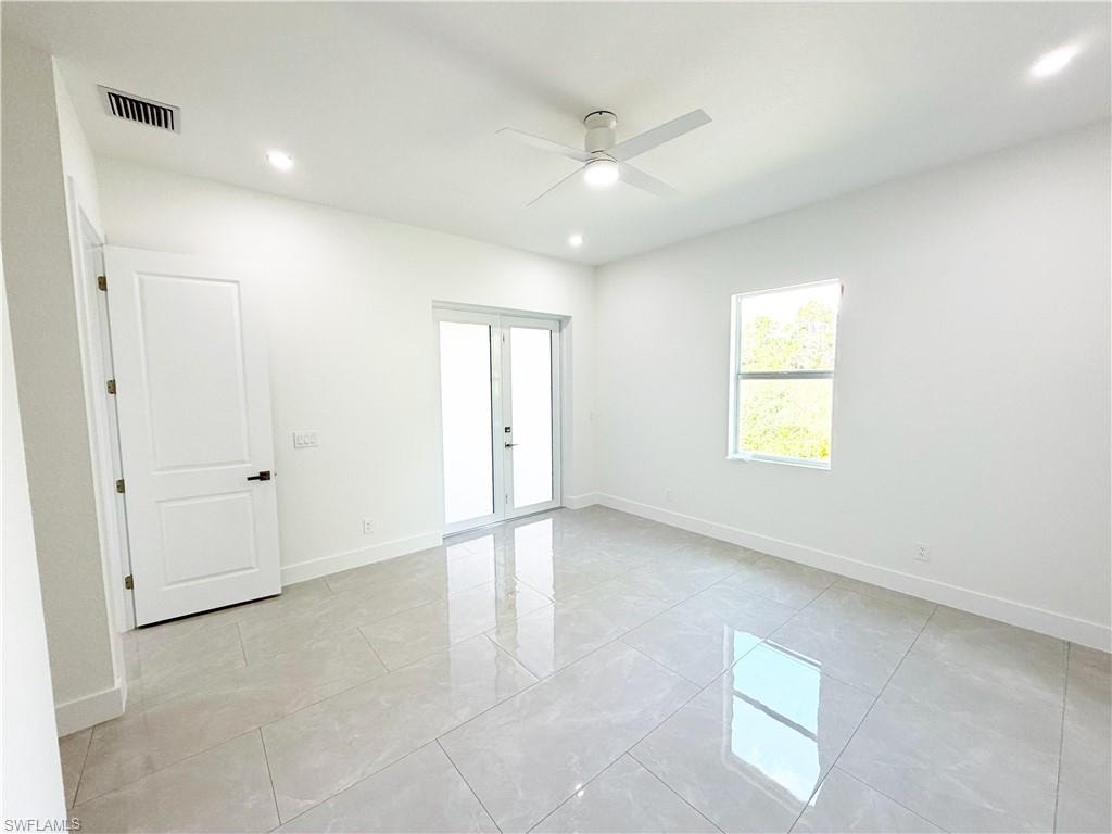 Spacious room featuring tile flooring, white walls, and a contemporary ceiling fan