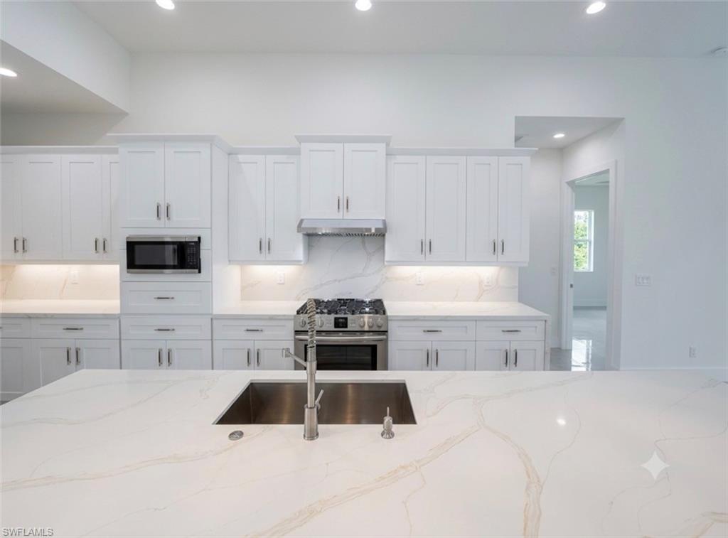 Spacious kitchen featuring white shaker cabinetry and integrated stainless steel appliances