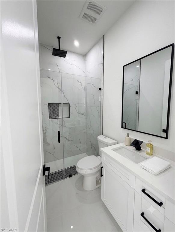 Contemporary bathroom featuring a frameless glass shower enclosure, a rain showerhead, a recessed shower niche, a white vanity with integrated sink, and a black-framed mirror
