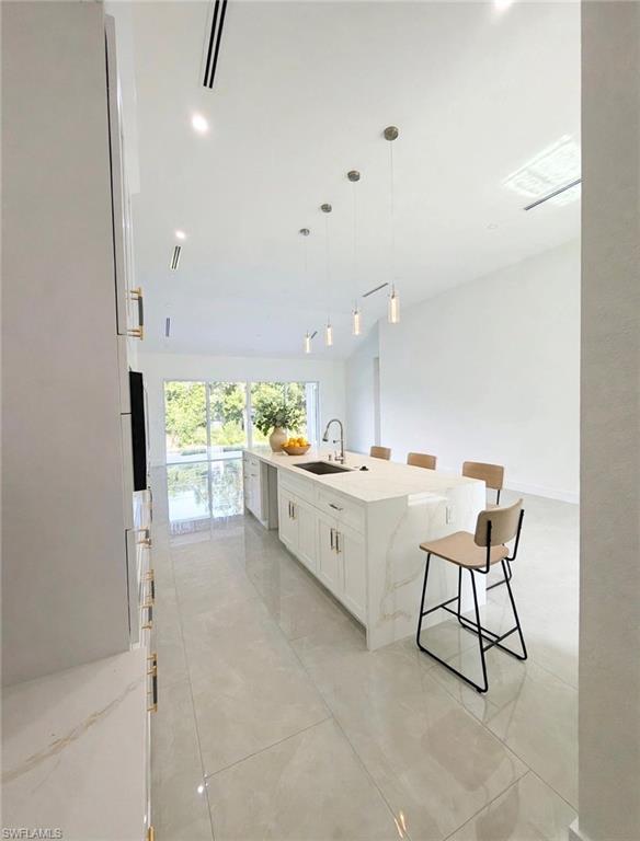 Spacious kitchen featuring a large central island with waterfall countertop, integrated sink, and ample seating