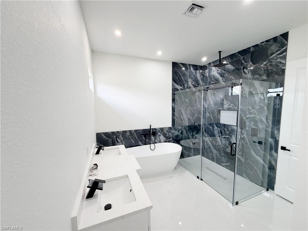 Spacious bathroom featuring a frameless glass shower enclosure with floor-to-ceiling dark marble-look tile, a freestanding soaking tub, and a dual vanity with undermount sinks and matte black fixtures