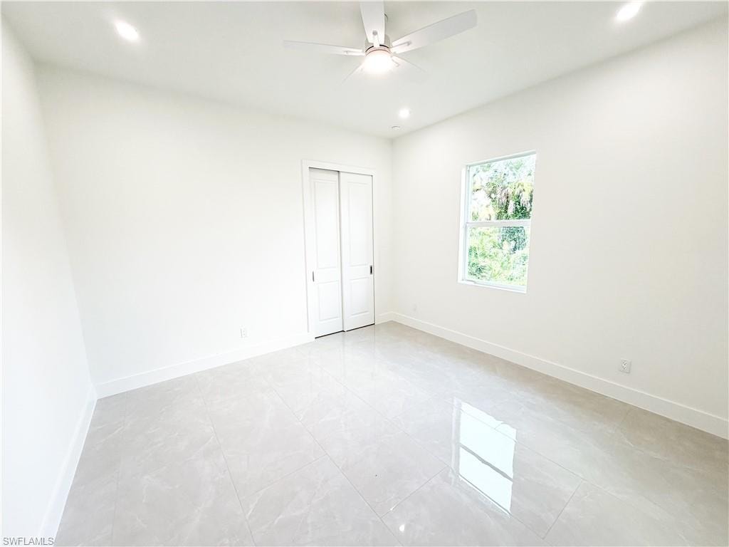 Bright room featuring tile flooring, a window providing natural light, a ceiling fan with integrated lighting, recessed ceiling lights, and bi-fold closet doors