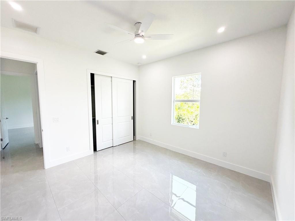 Bright interior space featuring large format tile flooring, a window providing natural light, and a modern ceiling fan with integrated lighting