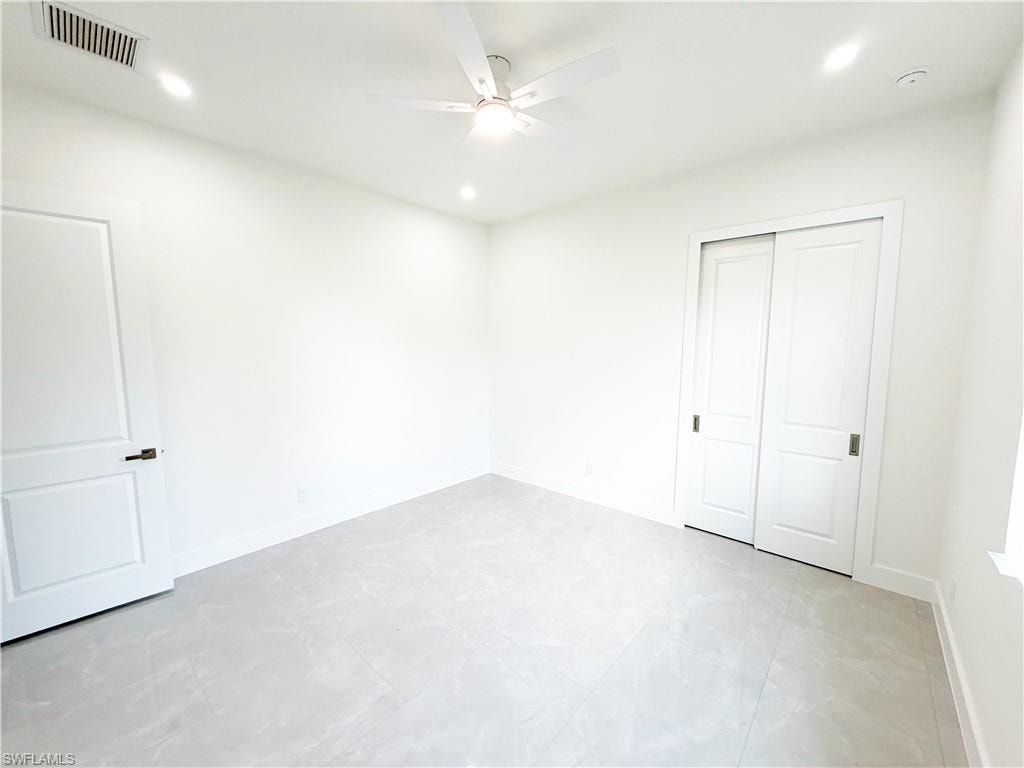 Bright interior space featuring light-toned tile flooring, a ceiling fan with integrated lighting, and recessed ceiling lights