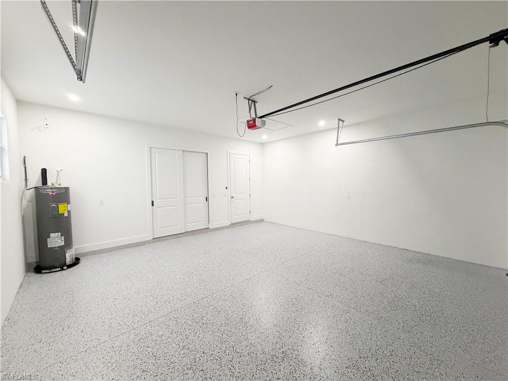 Spacious garage featuring a durable epoxy floor, recessed lighting, white painted walls, and built-in sliding panel doors