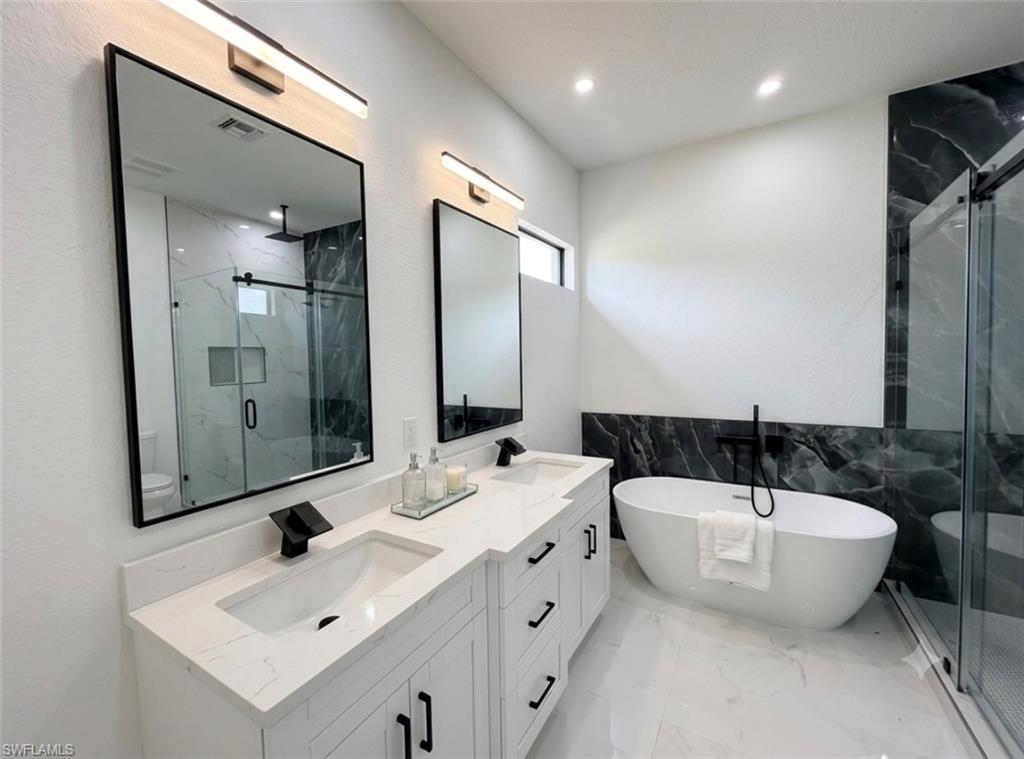 Double vanity with white cabinetry, quartz countertops, and matte black fixtures