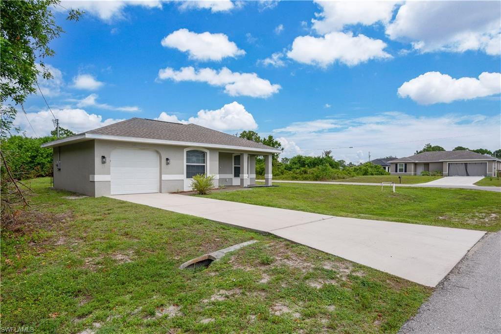 Contemporary single-story residence featuring a neutral stucco exterior, a gray shingled roof, an integrated garage, a covered front entry with columns, and a concrete driveway
