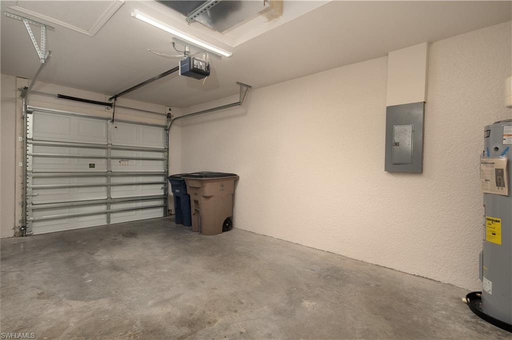 Single-car garage featuring a sectional overhead door with an automatic opener, concrete flooring, and a water heater