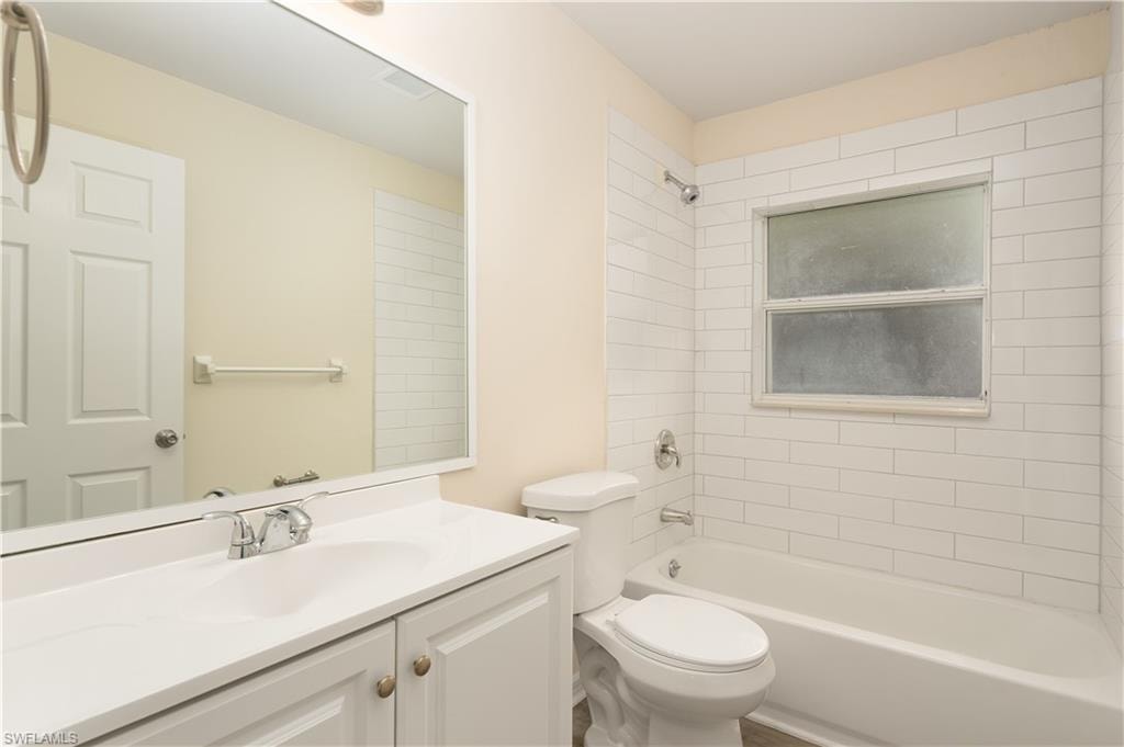 Bathroom featuring a white subway tile shower surround, a full bathtub, a white vanity with integrated sink, and a chrome faucet