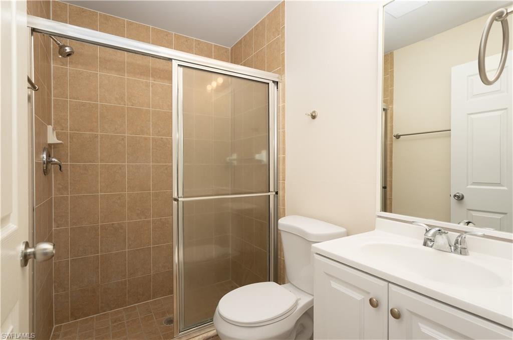 Bathroom featuring a glass-enclosed shower with full tile surround, white vanity with integrated sink, chrome faucet, and overhead vanity lighting