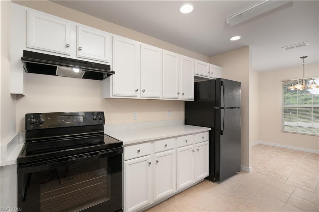 Kitchen featuring white cabinetry, light-colored countertops, black appliances, recessed lighting, and tile flooring