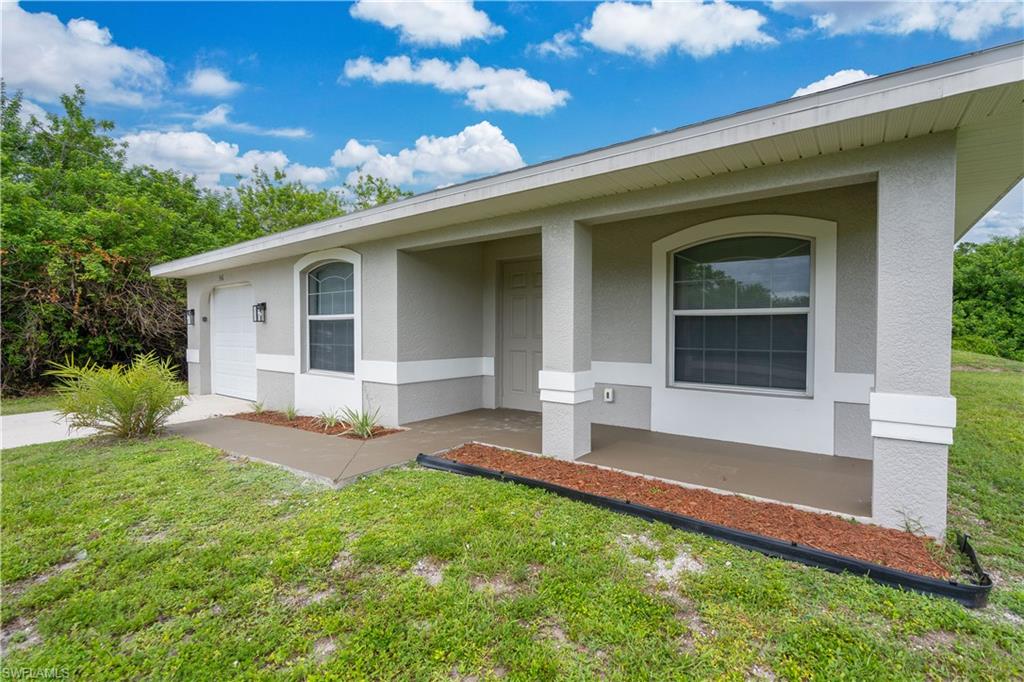Neutral tone exterior with a covered entry, arched windows, and an integrated garage