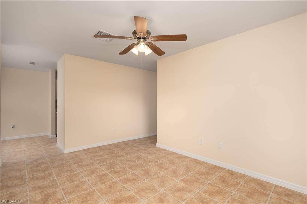 Spacious room featuring neutral wall tones, square tile flooring, white baseboards, a ceiling fan with integrated lighting, and recessed ceiling vents