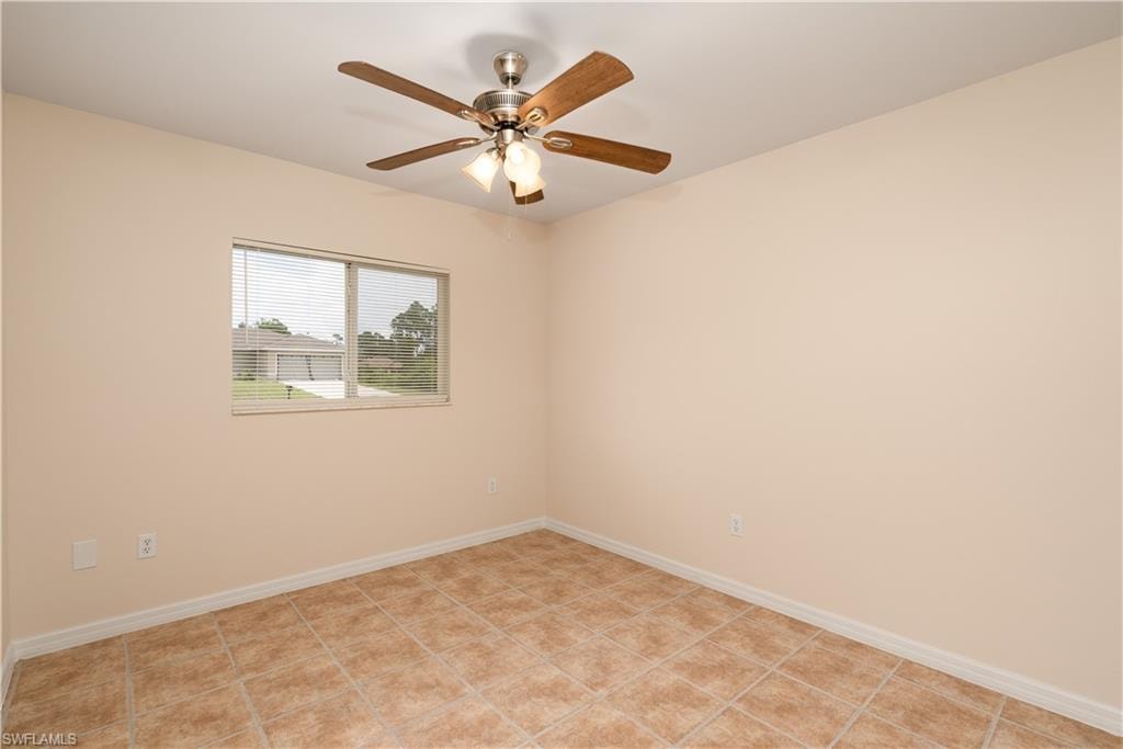 Neutral-toned room featuring a window with blinds, tile flooring, a ceiling fan with integrated lighting, and white baseboards