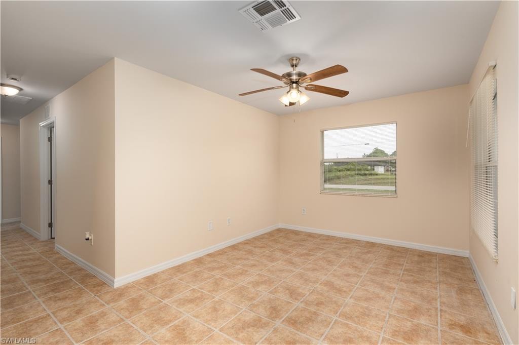 Living space featuring tile flooring, neutral wall tones, a ceiling fan with integrated lighting, and window with blinds