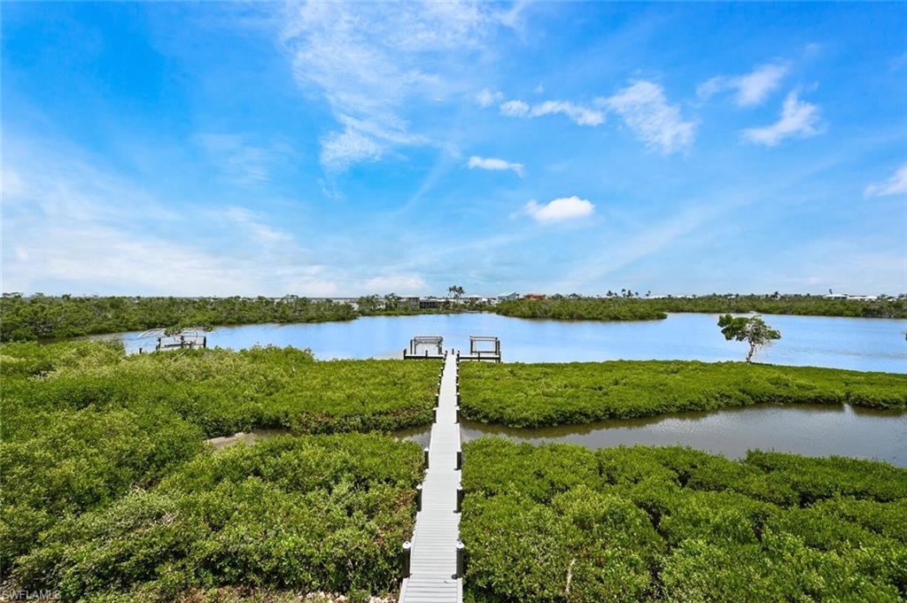 Waterfront property featuring a wooden dock extending into calm waters, surrounded by lush green foliage