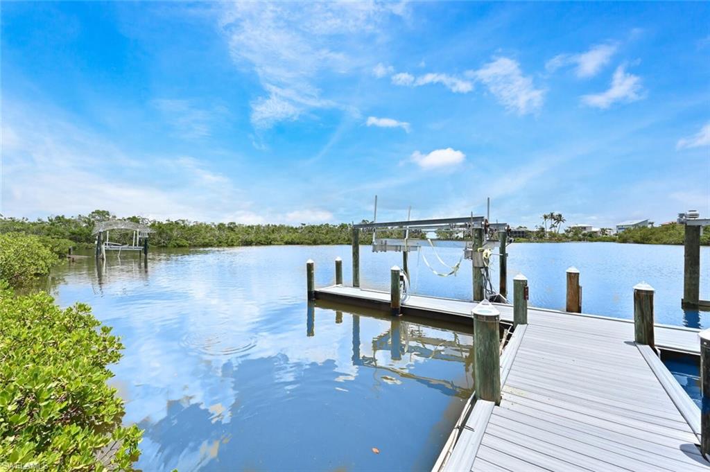 Waterfront property featuring a private dock with a boat lift, composite decking, and wooden pilings