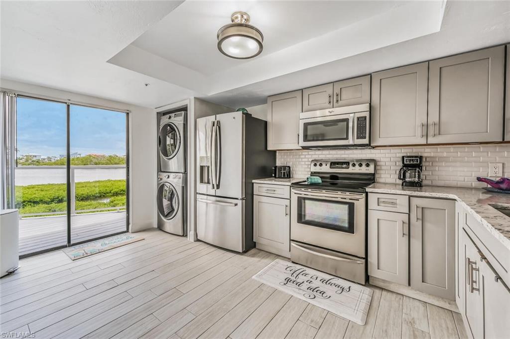 Modern kitchen featuring light gray cabinetry, stainless steel appliances, a subway tile backsplash, and light wood-finish flooring