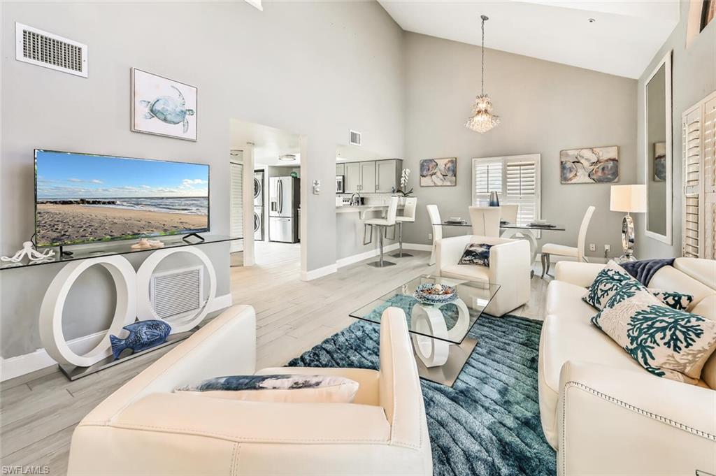 Vaulted ceilings highlight this living area featuring wood-finish flooring and a contemporary chandelier