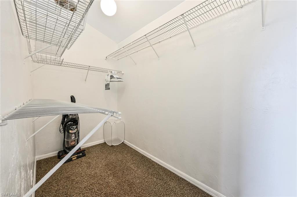 Walk-in closet featuring built-in wire shelving, white walls, white baseboards, and brown carpet flooring