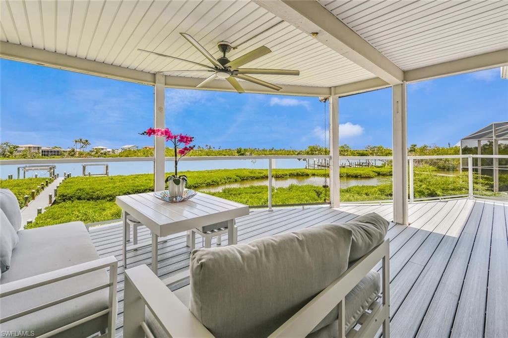 Covered outdoor deck with water frontage, featuring composite decking, a ceiling fan, and a clear panel railing system