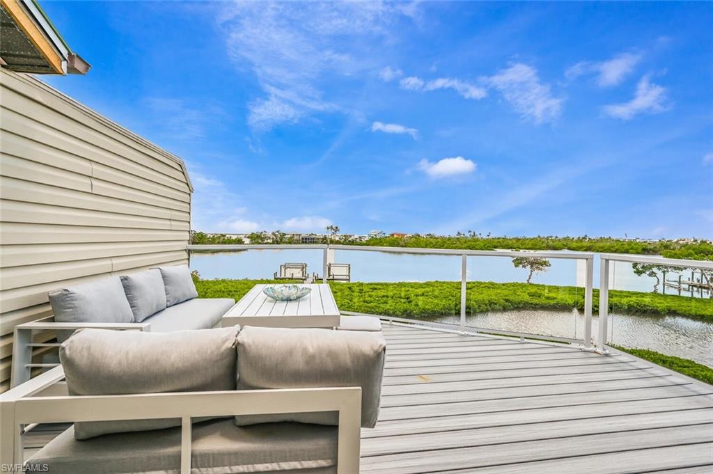 Expansive waterfront deck featuring a composite wood-finish surface, clear glass panel railings, and direct water access with a private dock