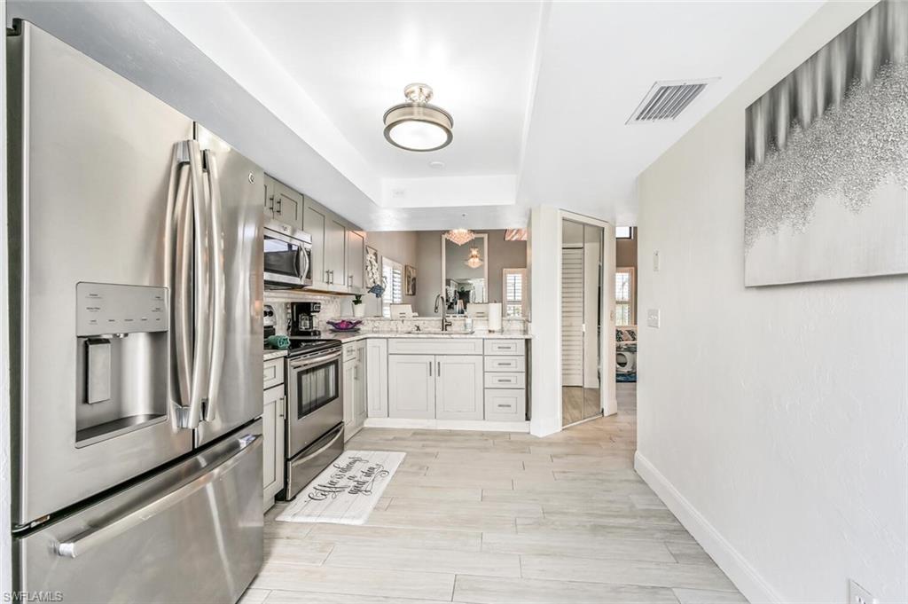 Kitchen featuring stainless steel appliances, light-toned cabinetry, light-toned countertops, and plank-style flooring