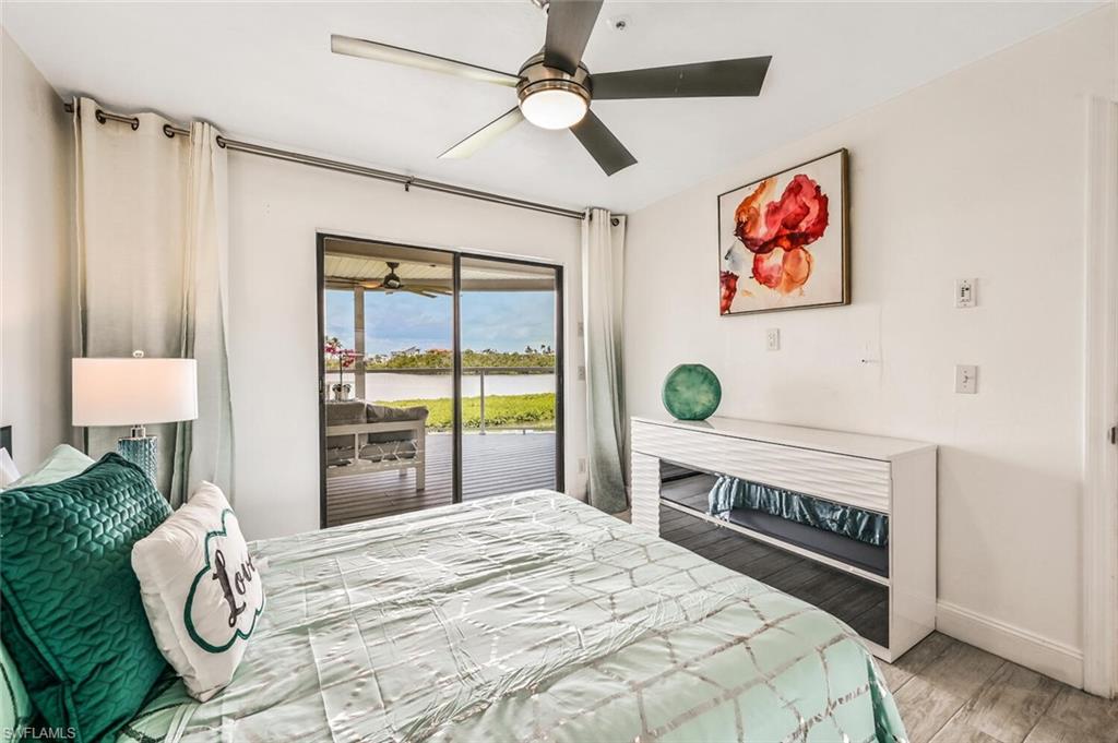 Sliding glass doors opening to a private patio, featuring a ceiling fan, recessed lighting, wood-finish flooring, and a modern dresser with reflective accents