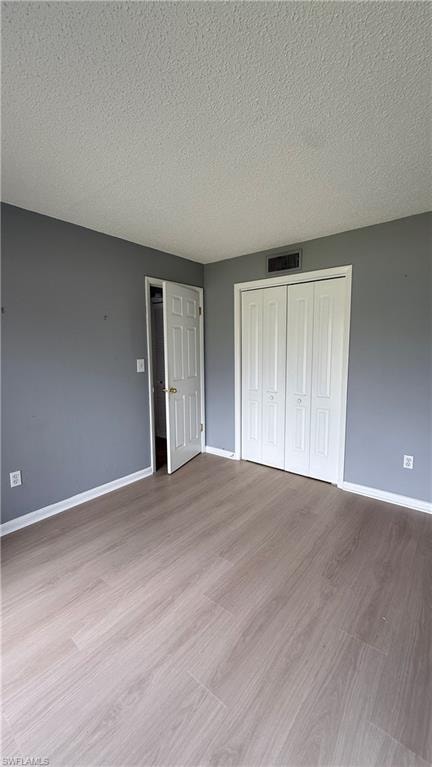 Wood-finish flooring, white bi-fold closet doors, white baseboards, and a paneled interior door